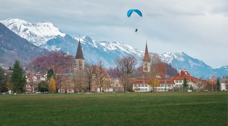 Tandem paraglider on final approach to land on the Höhematte field in central Interlaken
