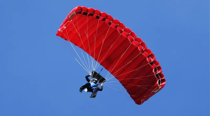 Skydiver under an open canopy descending towards the Reichenbach valley