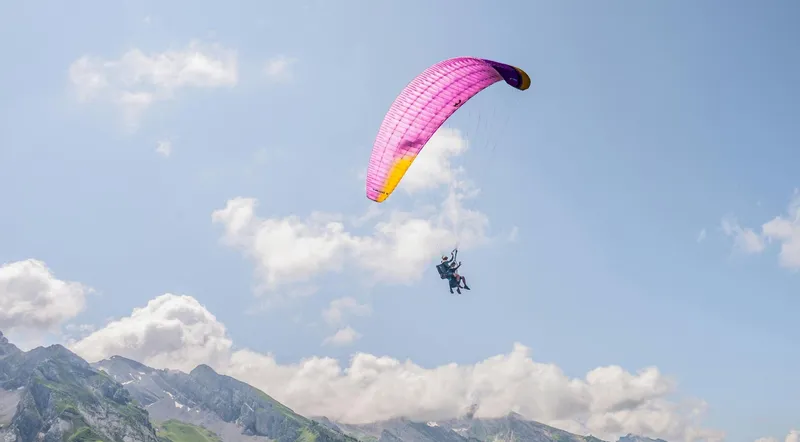 Tandem paraglider flying above a layer of cloud over Interlaken